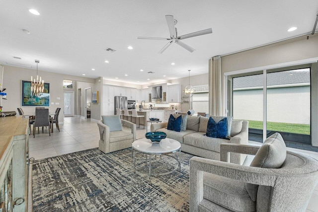 living room featuring light tile patterned floors, visible vents, ceiling fan with notable chandelier, and recessed lighting