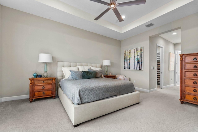 bedroom with baseboards, a tray ceiling, visible vents, and light colored carpet