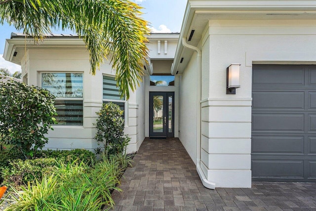 entrance to property featuring a garage and stucco siding