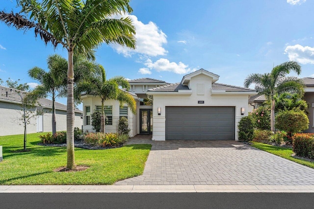 view of front of house with a garage, decorative driveway, a front lawn, and stucco siding