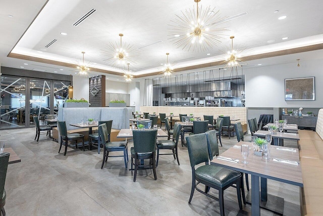 dining space with visible vents, a raised ceiling, concrete flooring, a chandelier, and recessed lighting