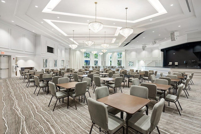 dining area with crown molding, a raised ceiling, a towering ceiling, and a decorative wall