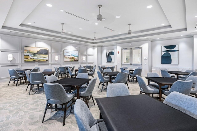 dining space featuring light carpet, a tray ceiling, a decorative wall, and recessed lighting