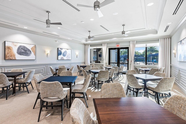 dining room with a wainscoted wall, ceiling fan, and a raised ceiling