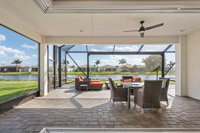 view of patio with a water view, a lanai, a ceiling fan, and outdoor dining space