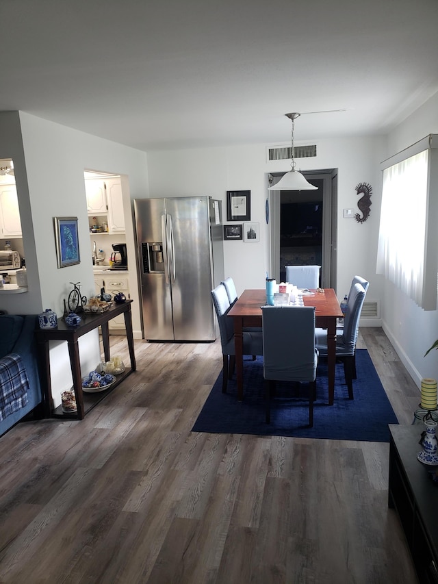 dining space with wood finished floors, visible vents, and baseboards