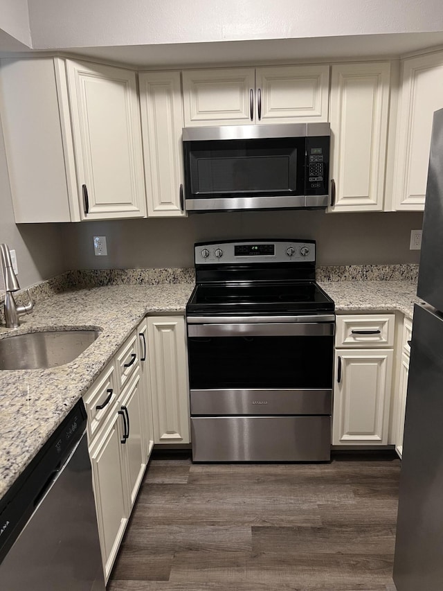 1548 SE Royal Green Cir Unit 105, Port Saint Lucie, FL 34952 - kitchen with stainless steel appliances, a sink, white cabinetry, dark wood-style floors, and light stone countertops