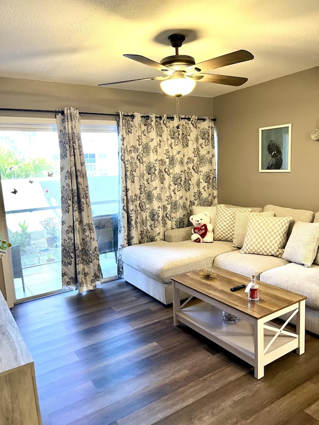 living room with a textured ceiling, wood finished floors, and a ceiling fan