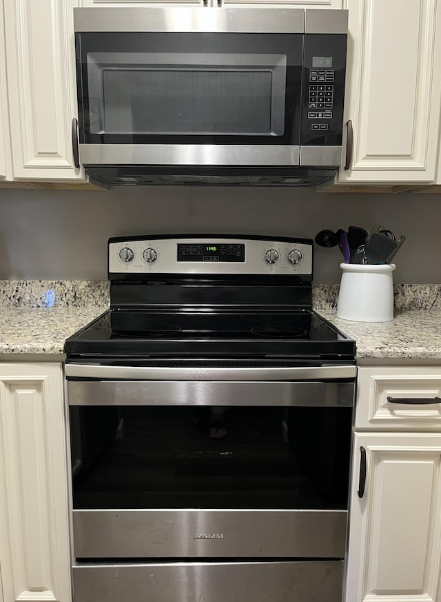 1548 SE Royal Green Cir Unit 105, Port Saint Lucie, FL 34952 - kitchen featuring appliances with stainless steel finishes, white cabinetry, and light stone counters