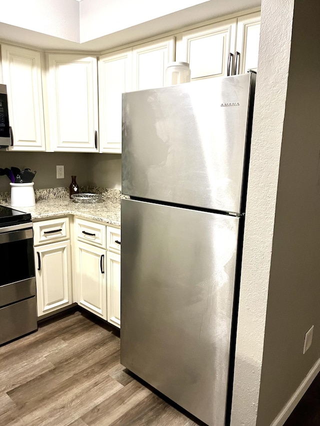 1548 SE Royal Green Cir Unit 105, Port Saint Lucie, FL 34952 - kitchen with stainless steel appliances, wood finished floors, light stone counters, and white cabinets