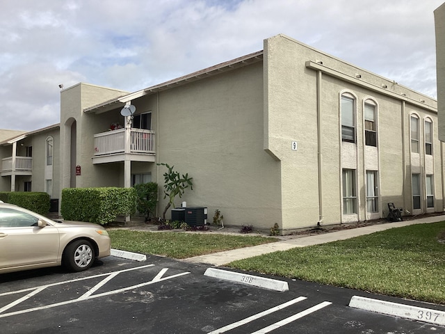 view of property featuring uncovered parking and central air condition unit