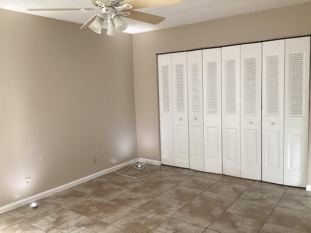 unfurnished bedroom featuring light tile patterned floors, a closet, a ceiling fan, and baseboards