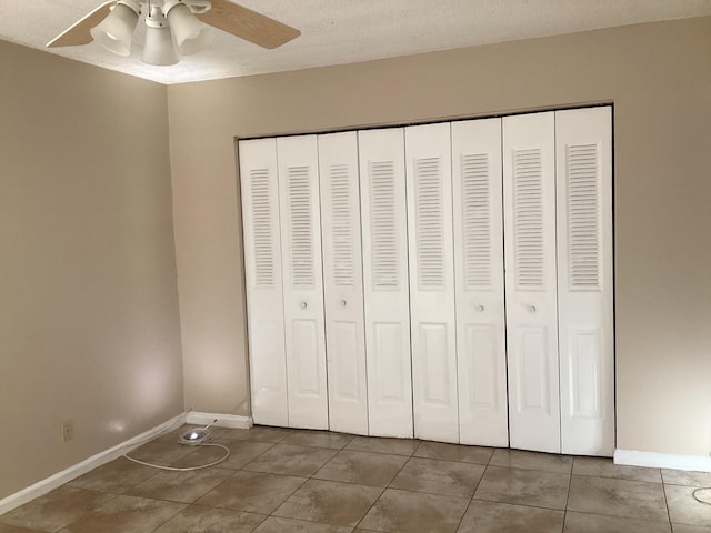 unfurnished bedroom with ceiling fan, baseboards, a closet, and tile patterned floors