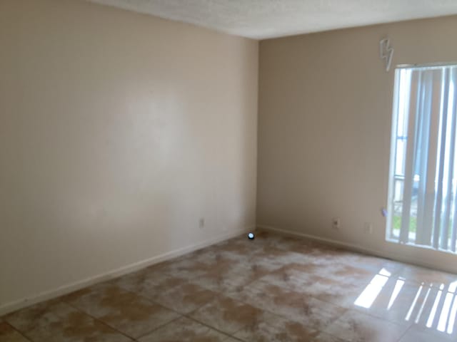 unfurnished room with tile patterned flooring and baseboards