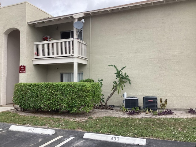 view of building exterior with uncovered parking and central AC unit