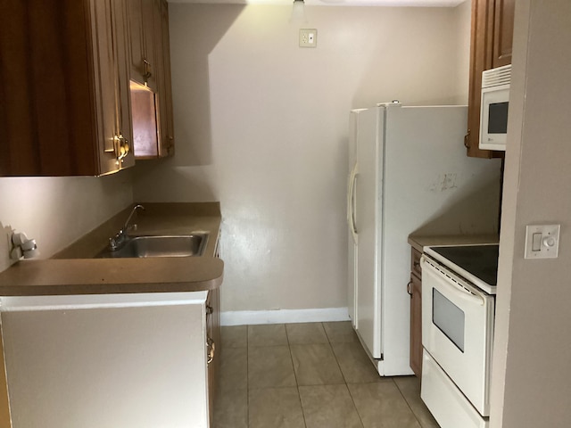 kitchen featuring white appliances, light tile patterned flooring, a sink, and baseboards