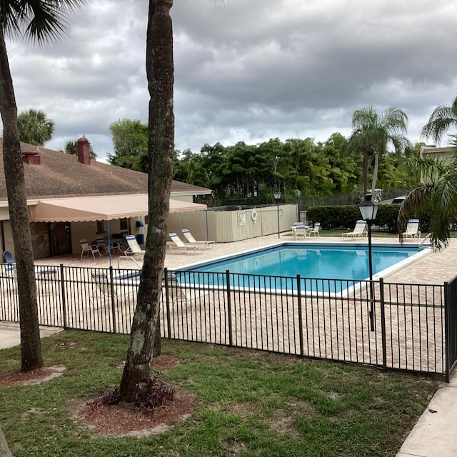 community pool with fence and a patio