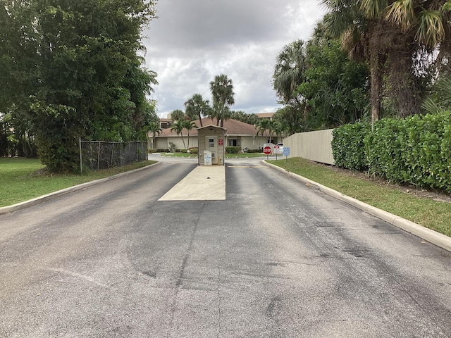 view of street with traffic signs, a gated entry, and curbs