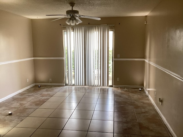 spare room featuring a textured ceiling, tile patterned flooring, a ceiling fan, and baseboards