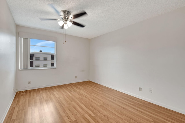 empty room with light wood-type flooring, ceiling fan, a textured ceiling, and baseboards