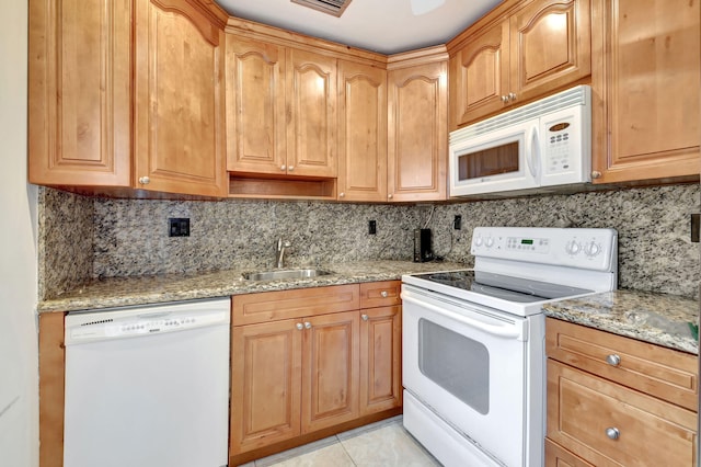 kitchen with light stone counters, white appliances, a sink, and decorative backsplash