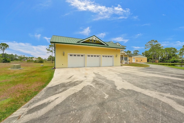 view of front of house featuring concrete driveway, metal roof, an attached garage, a standing seam roof, and a front yard