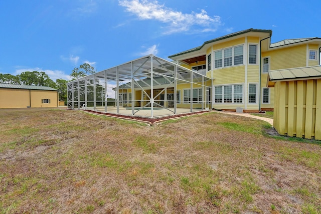 rear view of property with glass enclosure, a lawn, and a patio