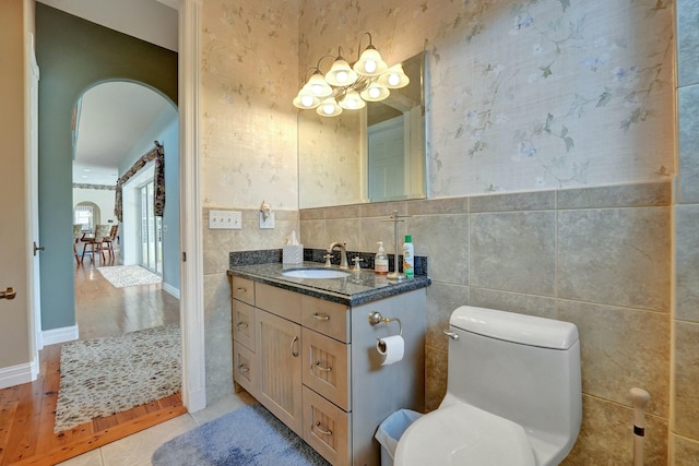 bathroom featuring wallpapered walls, toilet, tile patterned flooring, vanity, and tile walls