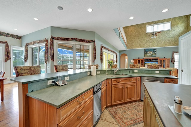 kitchen featuring a skylight, arched walkways, brown cabinetry, a center island, and a sink