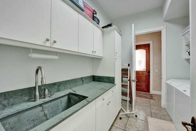 kitchen with baseboards, white cabinets, a sink, and washing machine and clothes dryer