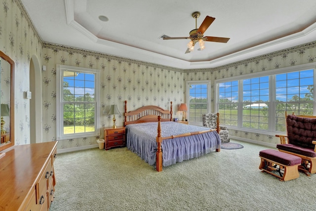 carpeted bedroom featuring arched walkways, a raised ceiling, baseboards, and wallpapered walls