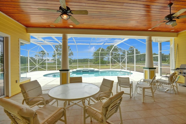 view of patio / terrace with glass enclosure, a pool with connected hot tub, and a ceiling fan