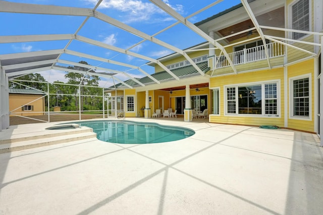 view of swimming pool with glass enclosure, a patio, a pool with connected hot tub, and a ceiling fan