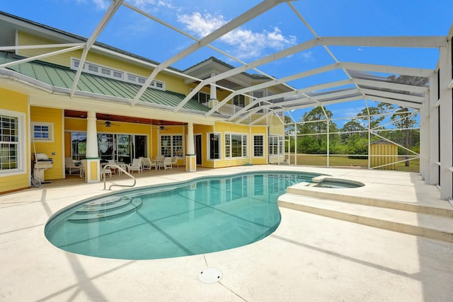 pool featuring glass enclosure, a patio area, a ceiling fan, and an in ground hot tub