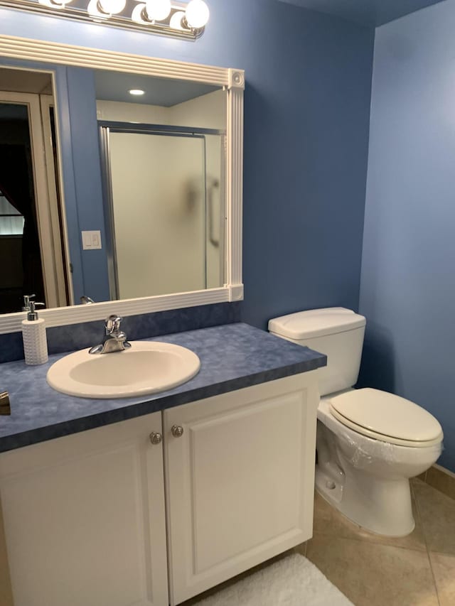 bathroom with toilet, vanity, a shower stall, and tile patterned floors