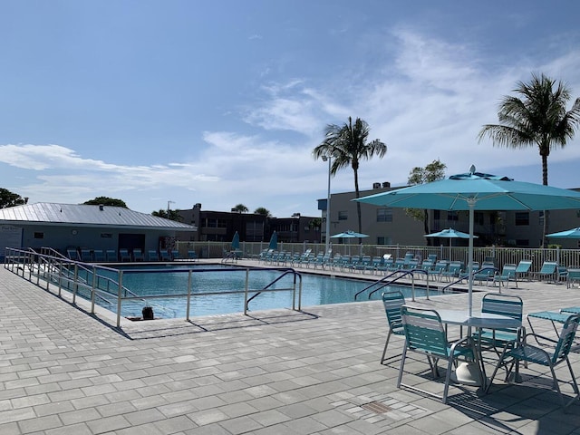 community pool with a patio and fence