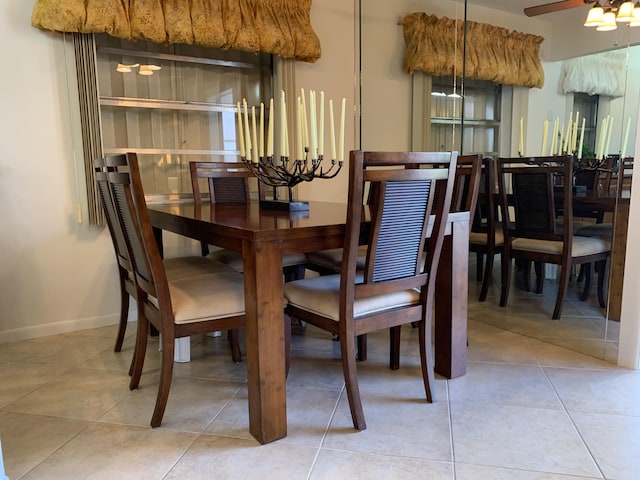 tiled dining area featuring ceiling fan and baseboards