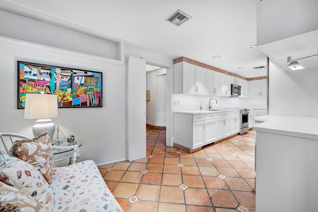 kitchen with visible vents, white cabinets, appliances with stainless steel finishes, backsplash, and a sink