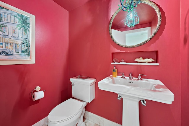 bathroom with toilet, tile patterned flooring, baseboards, and a sink