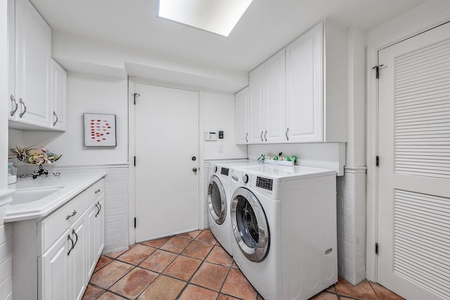 clothes washing area featuring light tile patterned floors, washer and clothes dryer, and cabinet space