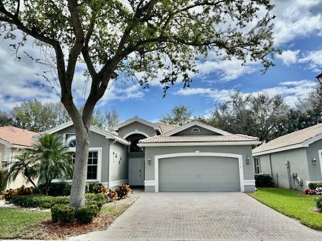 ranch-style home with a garage, decorative driveway, a tiled roof, and stucco siding