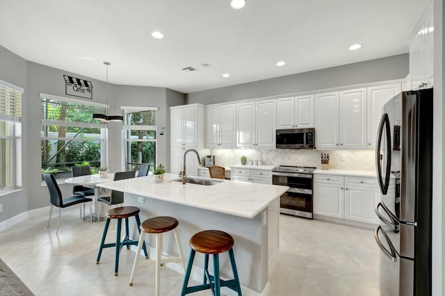 kitchen featuring stainless steel appliances, tasteful backsplash, a sink, and white cabinets