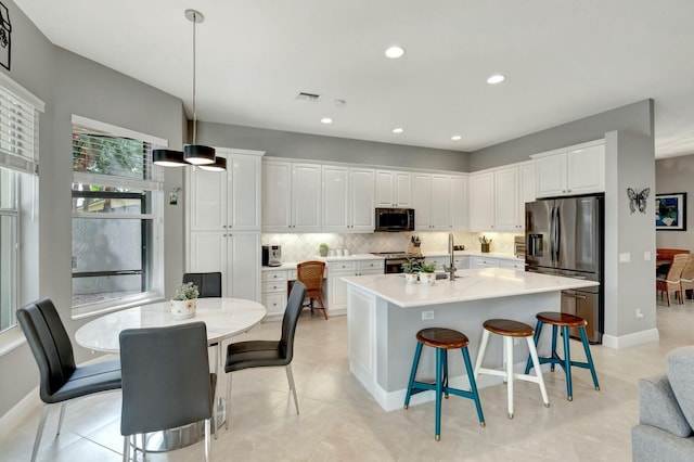 kitchen with stainless steel appliances, a breakfast bar, white cabinets, and backsplash