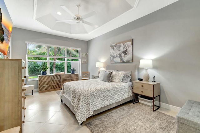 bedroom featuring light tile patterned flooring, a raised ceiling, a ceiling fan, and baseboards