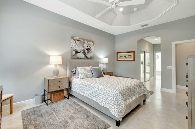 bedroom with arched walkways, visible vents, baseboards, a closet, and a tray ceiling