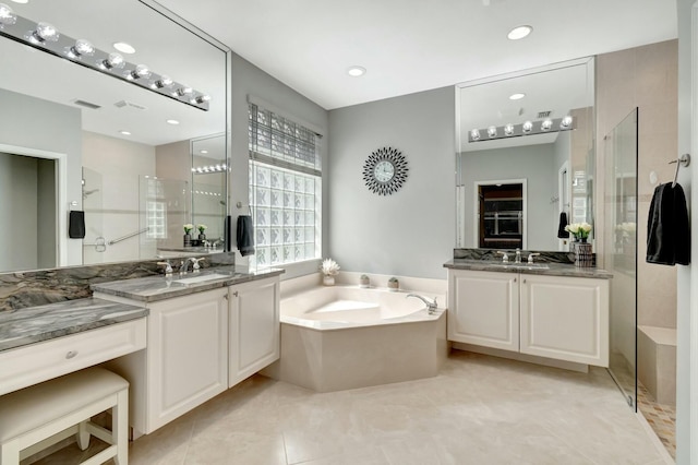 full bathroom with visible vents, two vanities, a shower stall, and a bath