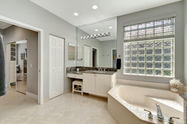 bathroom featuring baseboards, a garden tub, vanity, and recessed lighting