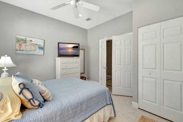 bedroom featuring lofted ceiling, light colored carpet, a ceiling fan, visible vents, and a closet