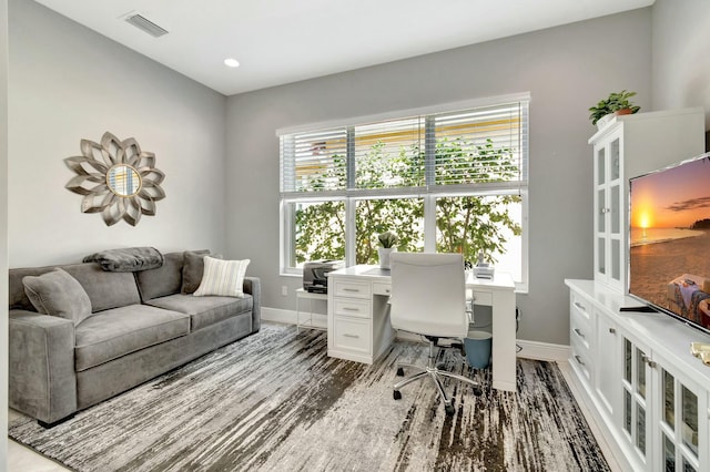 home office with plenty of natural light, visible vents, baseboards, and wood finished floors