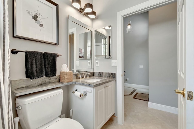 bathroom featuring toilet, baseboards, and vanity